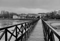 A black and white photo of a wooden bridge on a beach of a town on the Galician coast