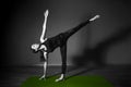 Black white photo of Young beautiful woman brunette in black clothes practice yoga ardha chandrasana in dark studio green mat