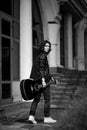 Black and white photo,young, handsome man, brunette with long hair,musician,walking around the city with a guitar, in jeans and a Royalty Free Stock Photo