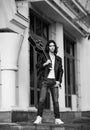 Black and white photo,young, handsome man, brunette with long hair,musician,walking around the city with a guitar, in jeans and a Royalty Free Stock Photo