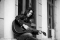 Black and white photo,young, handsome man, brunette with long hair,musician,walking around the city with a guitar, in jeans and a Royalty Free Stock Photo