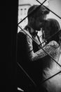 Black and white photo. Young stylish newlyweds are hugging behind old rustic door. wedding day