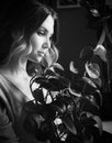The black-white photo depicts a beautiful young woman gazing at a houseplant she has grown herself. The gardening, plant care, and