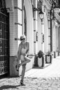 Black and white photograph of a fashionable stylish smiling girl on the city streets with a broken shoe heel