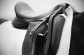 A black-white photograph of the a saddle, a stirrup and a white saddlecloth Royalty Free Stock Photo