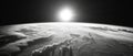 A black and white photograph of the sun rising or setting over the earth's surface, with minimal atmospheric Royalty Free Stock Photo
