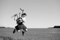 Black white photography of man jumping high with pipes in Scottish traditional kilt on summer field outdoors