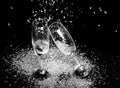 Black and white photo of two champagne glasses with icing falling on black background