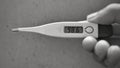 A Black and white picture of a digital farenheit thermometer showing normal body temperature which is 98.6 degree Fahrenheit