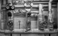 Black-and-white picture of heating pipes in the cellar with shut-off valves, thermometers, valves and throttles, jacket made of Royalty Free Stock Photo