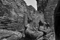 Row of headless Buddha images beside broken brick wall