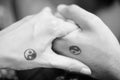 Black and white pictures. Two hands holding each other with yin and yang symbols. Royalty Free Stock Photo