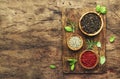 Black, white and pink rose peppers in bowls, assorted spices and spicy herbs on wooden rustic kitchen table, copy space, top view Royalty Free Stock Photo