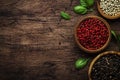 Black, white and pink rose peppers in bowls, assorted spices and spicy herbs on wooden rustic kitchen table, copy space, top view Royalty Free Stock Photo