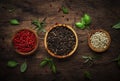 Black, white and pink rose peppers in bowls, assorted spices and spicy herbs on wooden rustic kitchen table, copy space, top view Royalty Free Stock Photo