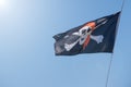 Black and white pirate flag is flying on blue sky Royalty Free Stock Photo