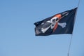 Black and white pirate flag is flying on blue sky Royalty Free Stock Photo