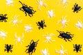 Black and white plastic flies and beetles lie randomly on a yellow cardboard background Royalty Free Stock Photo