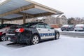 Black and white police car parked on a snowy neighborhood on a rainy winter day