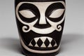 Black and white porcelain tiki mask with teeth on white background.