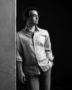 Black and white portrait of adult man in shirt and jeans standing leaning concrete wall and looking aside Royalty Free Stock Photo