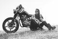 Black-and-white portrait of a beautiful biker woman sitting by her motorcycle Royalty Free Stock Photo