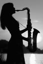 Black and white portrait of beautiful girl playing the saxophone at the lake Royalty Free Stock Photo