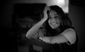 Black and white portrait of a beautiful Indian girl smiling while sitting in a dark room Royalty Free Stock Photo