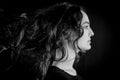 Black and white portrait of a beautiful young Italian woman with very long brown hair in profile looking seriously in front of her