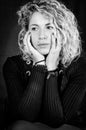 Black and white portrait of a beautiful young woman with blond curly hair holding her face with her hands Royalty Free Stock Photo