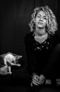 Black and white portrait of a beautiful young woman with blond curly hair sitting on the ground looking bored with a cat Royalty Free Stock Photo