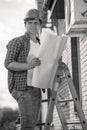Black and white portrait of male constrcution engineer standing on stepladder and holding blueprints Royalty Free Stock Photo