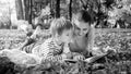 Black and white portrait of family reading story book while lying on ground at park Royalty Free Stock Photo