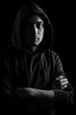 Black and white portrait of a handsome young blue-eyed hooded man with his arms crossed Royalty Free Stock Photo