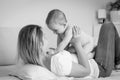 Black and white portrait of happy mother lying on bed and playing with baby Royalty Free Stock Photo