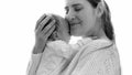 Black and white portrait of happy young mother hugging her little baby son against big window Royalty Free Stock Photo