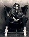 Black and white portrait of the imperious young woman sitting in the black chair.