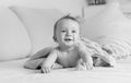 Black and white portrait of laughing baby boy lying under blanket on sofa Royalty Free Stock Photo