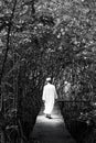 Black and white portrait of male muslim in traditional clothing walking in a mangrove forest. Fantasy of light, shadow and