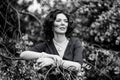 Black and white portrait of a middle-aged brunette in a blue dress next to a blooming linden Royalty Free Stock Photo