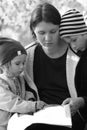 Black and white portrait of mother and two children reading a book Royalty Free Stock Photo