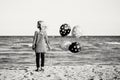 Pensive teenager white Caucasian child kid with bunch of balloons standing on beach Royalty Free Stock Photo