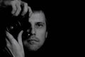 Black and white portrait of a photographer with an open eye with an old SLR camera on a dark background close-up Royalty Free Stock Photo