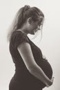 Black and white portrait of pregnant woman in profile with hands on her stomach on white background, future life concept Royalty Free Stock Photo