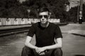 Black and white portrait of serious handsome young man sitting on a step at railway station Royalty Free Stock Photo