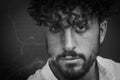 Black and white portrait of a serious young man with a beard and curly hair with puffs of cigarette smoke