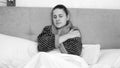 Black and white portrait of sick woman wearing bathrobe lying under blanket in bed Royalty Free Stock Photo
