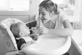 Black and white portrait of smiling mother feeding her baby in h Royalty Free Stock Photo