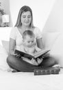 Black and white portrait of smiling mother reading book to her b Royalty Free Stock Photo