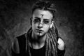 Black and white portrait of a young woman with dreadlocks against dark background Royalty Free Stock Photo